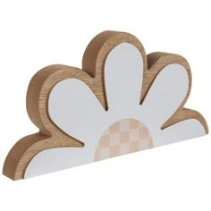 a white and brown flower shaped object on a wooden stand with checkerboard background