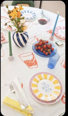 a white table topped with plates and bowls filled with fruit on top of a table