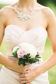 a woman in a strapless dress holding a pink and white bouquet with greenery