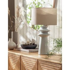 a white table lamp sitting on top of a wooden dresser