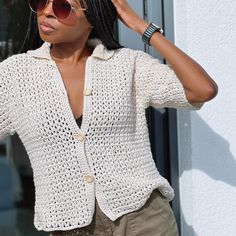 a woman wearing sunglasses and a crochet jacket