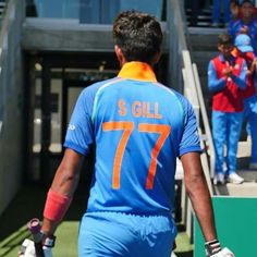 two men in blue uniforms walking towards the dugout