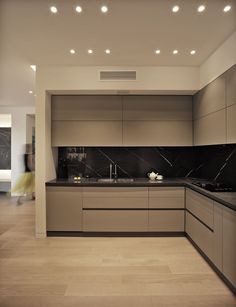 a modern kitchen with black counter tops and marble backsplash