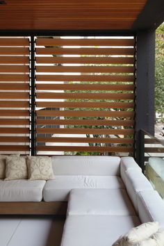 a white couch sitting under a window next to a wooden slatted wall in a living room