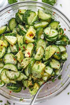 a glass bowl filled with cucumbers and seasoning on top of a table