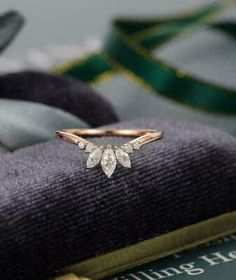 a gold ring with three pear shaped diamonds on it, sitting on top of a pile of fabric