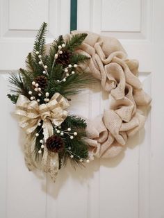 a wreath hanging on the front door decorated with pine cones, berries and burlocks