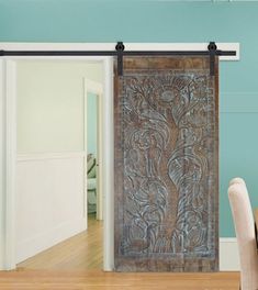 an ornate wooden door is open to the dining room and living room with blue walls