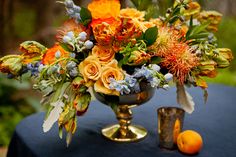 a vase filled with lots of flowers sitting on top of a blue cloth covered table