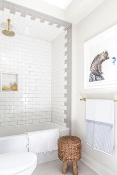 a bathroom with white tile walls and a wooden stool next to the bathtub on instagram