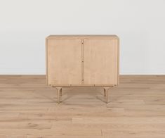 a wooden cabinet sitting on top of a hard wood floor next to a white wall