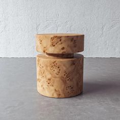 two wooden bowls sitting on top of each other in front of a white wall and concrete floor