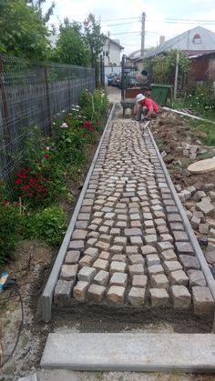 two men are working on a brick walkway