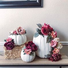 three white pumpkins decorated with flowers on a table