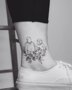 a woman's lower ankle tattoo with flowers on her left side and an image of two people holding hands