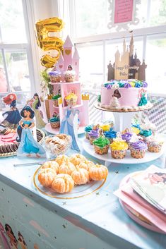 a table topped with lots of cakes and cupcakes