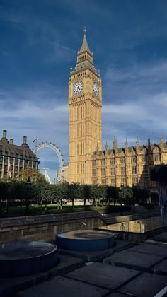 the big ben clock tower towering over the city of london, england with ferris wheel in the background