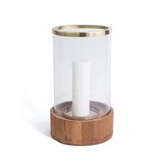 a white candle is in a glass container on a wooden stand with a wood base