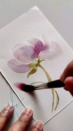 someone is painting a flower with watercolors on paper