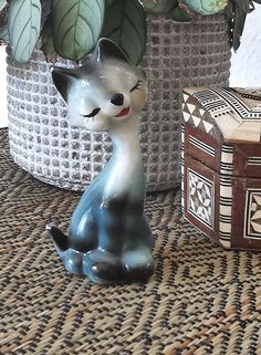 a ceramic figurine sitting on top of a table next to boxes and plants