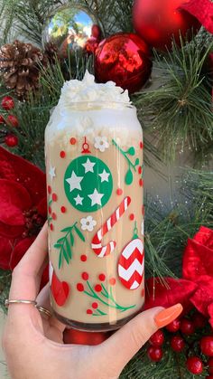 a hand holding a jar with christmas decorations on it