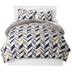 an image of a bed with black, yellow and white comforter sets on it