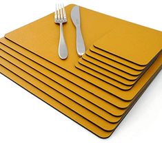 yellow placemats with forks and spoons on top of each other in front of a white background