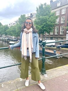 a woman standing next to a body of water wearing sunglasses and a scarf over her head