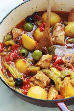 a pot full of stew with olives, potatoes and meat