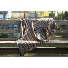 a blanket draped over a park bench on a sunny day