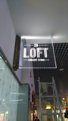 a sign that reads loft on the side of a building with people walking around it