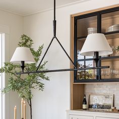 a dining room table with two lamps hanging over it