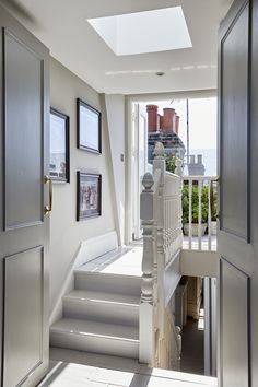 an open door leading to a white staircase with pictures on the wall and below it