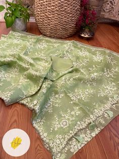 a green blanket sitting on top of a wooden floor next to a potted plant