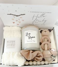 an open box containing a candle, teddy bear and other items to be used as a baby shower gift