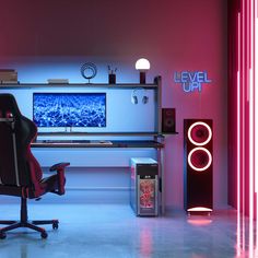 a computer desk with speakers and a monitor on it in a room lit by neon lights