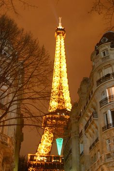 the eiffel tower lit up at night in paris, france with buildings around it