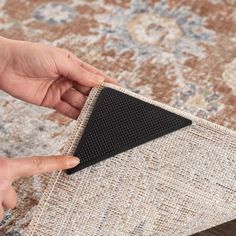 a person placing a black triangle on top of a rug