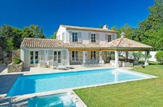 a house with a pool in front of it and a covered patio next to it