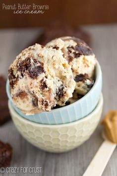 two scoops of ice cream in a bowl on a wooden table with peanut butter and chocolate chip cookies