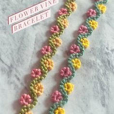 two crocheted flowers on a white surface next to a pink and yellow ribbon