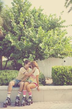 a man and woman sitting next to each other on a cement bench in front of trees