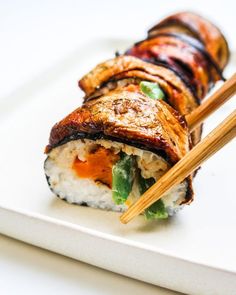 a white plate topped with sushi and chopsticks