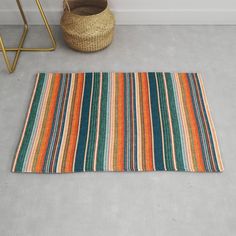 a multicolored striped rug on the floor next to a basket and planter