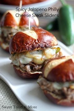 two hamburgers with meat and cheese are on a white plate