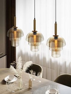 three glass pendant lights hanging over a dining room table