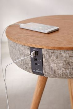 an electronic device is plugged into the side of a round table with wooden legs