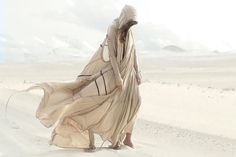 a woman is walking in the desert wearing a long dress with hood on her head