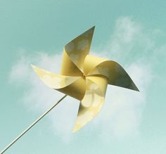 a yellow and white pinwheel flying in the sky