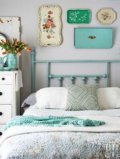 a white bed topped with lots of pillows next to a wall covered in framed pictures